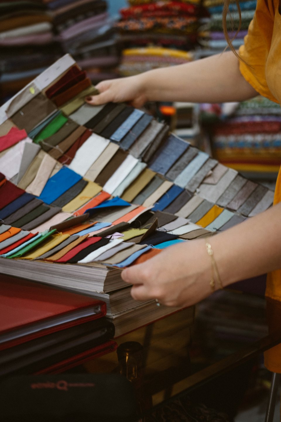 Hands selecting colorful fabric swatches from a book.