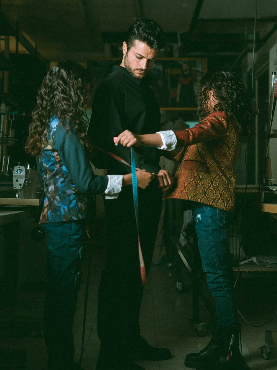 Two tailors measure a client for a custom suit.
