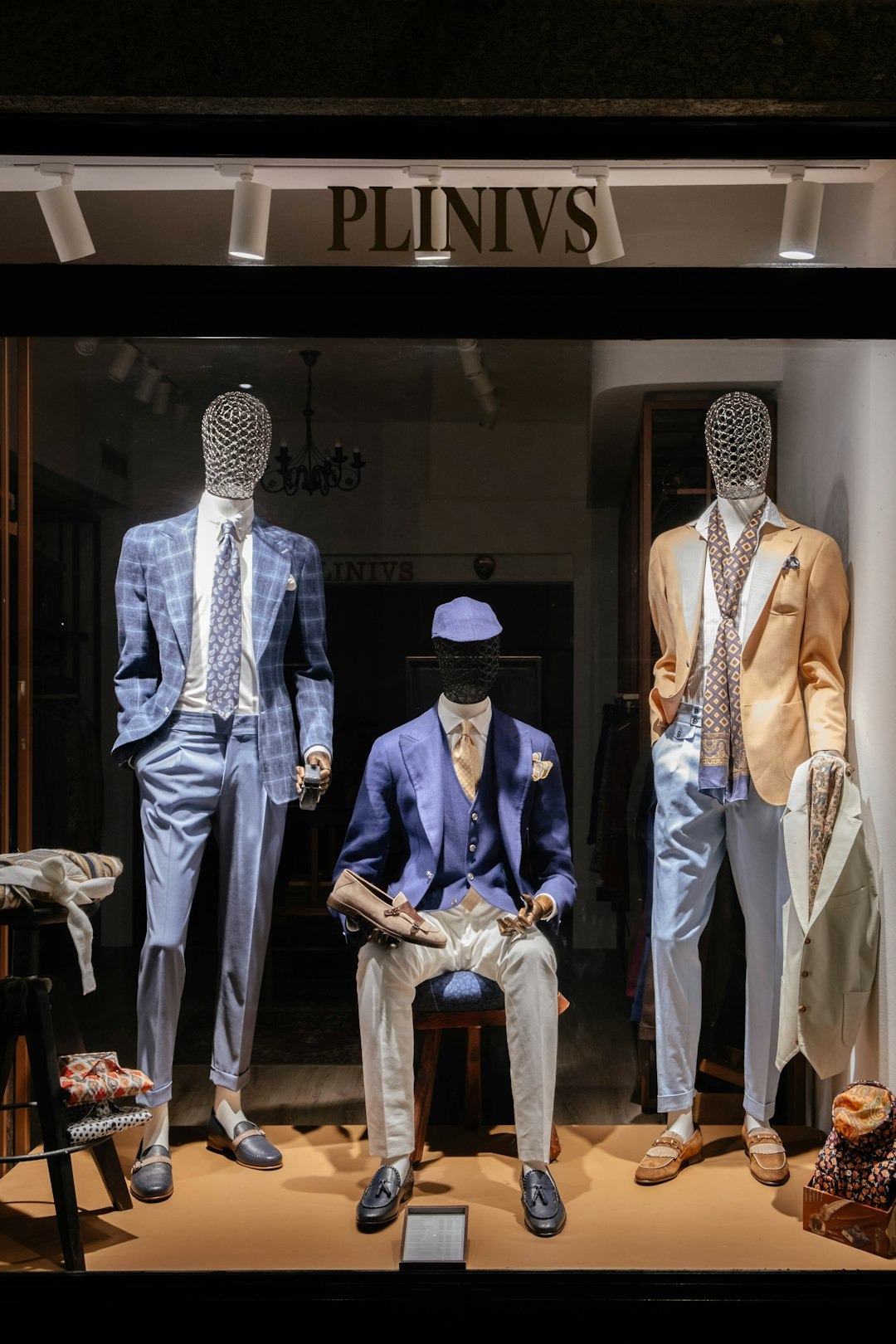 Mannequins in tailored suits displayed in a boutique window.