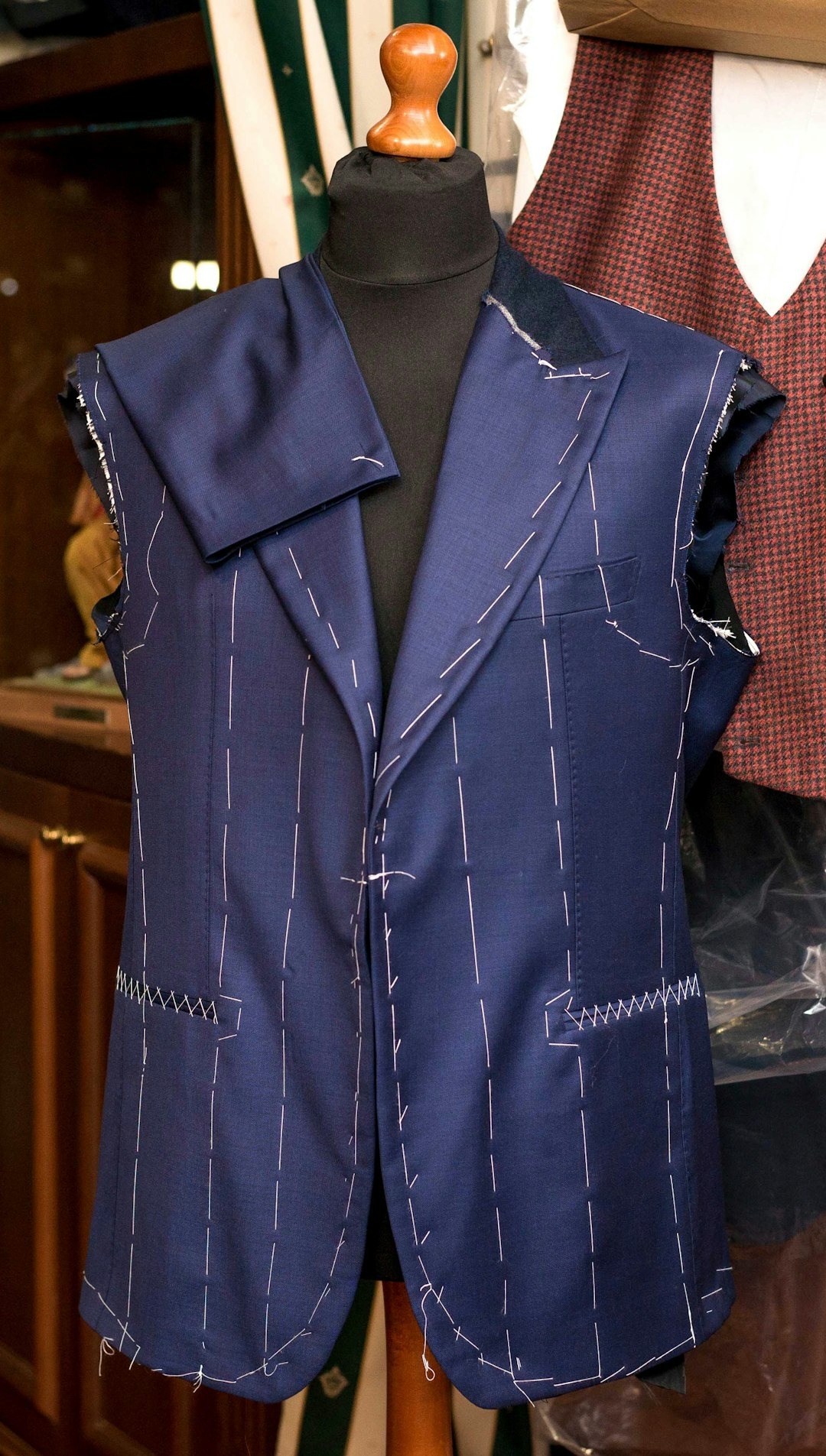 Navy blue blazer with basting stitches on a mannequin.